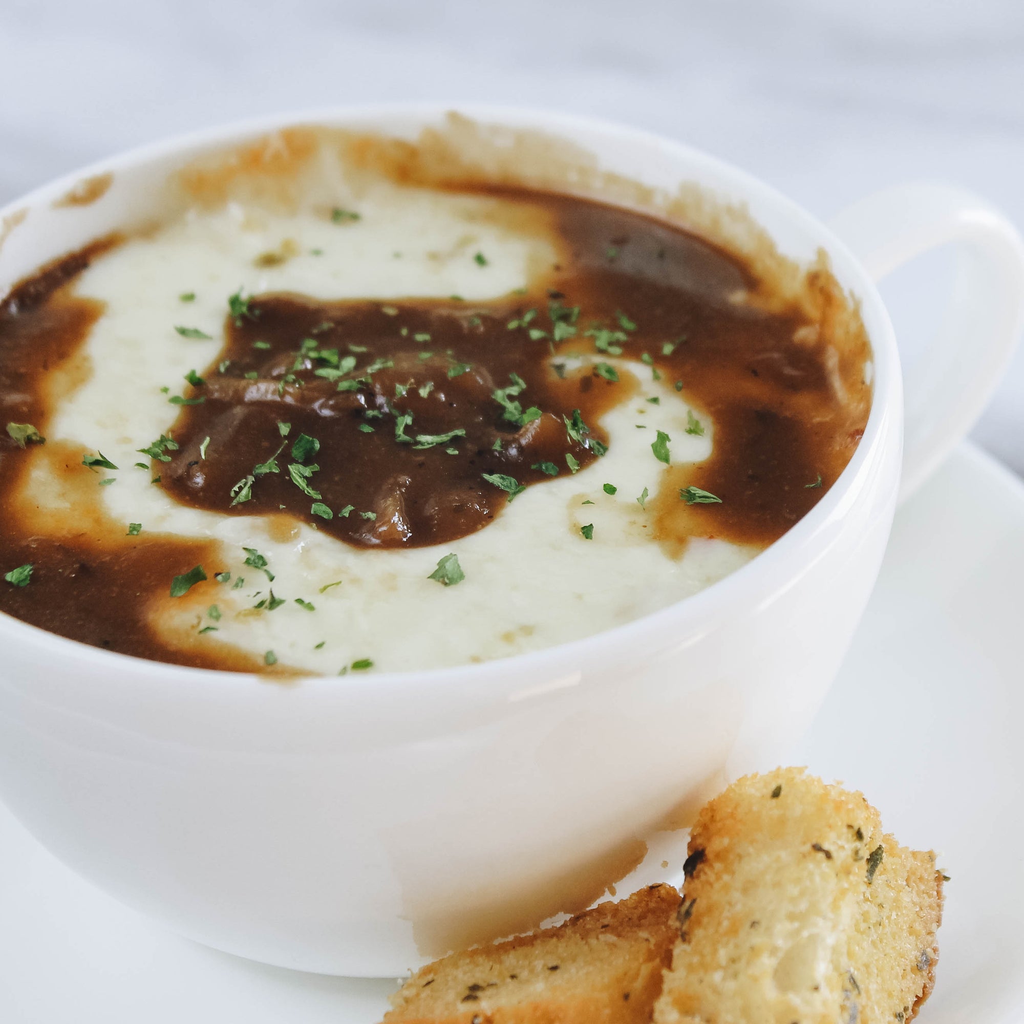 Cajun french onion soup recipe with melted cheese topped with parsley and croutons using The Cajun Spoon Brown Gravy Cajun Seasoning product